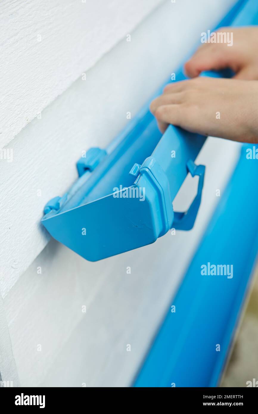 Attaching painted guttering planter to side of building Stock Photo