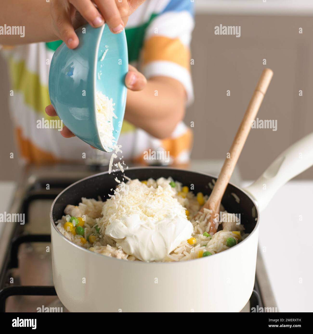 Making chicken risotto, adding parmesan cheese to saucepan of chicken