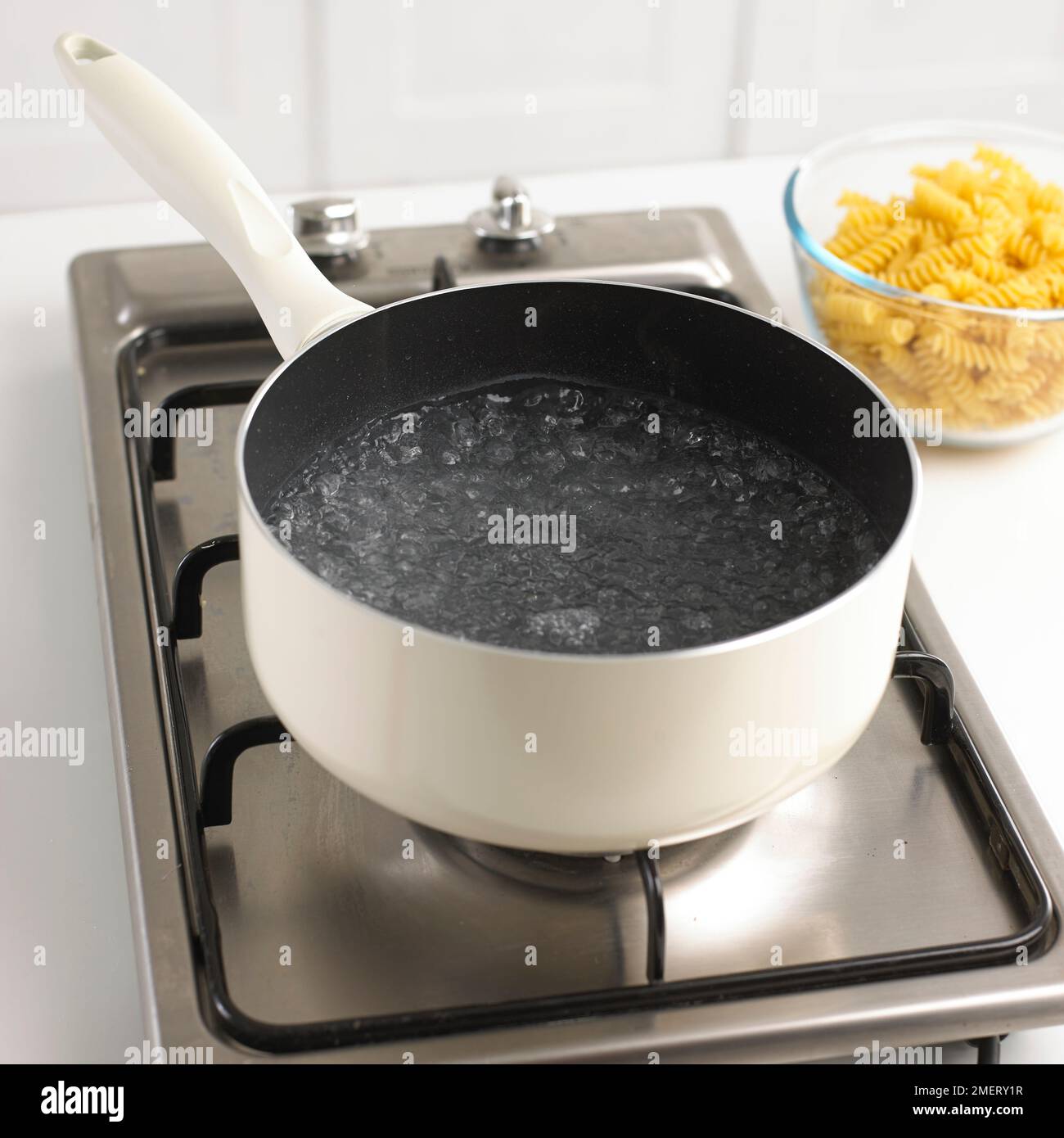 Saucepan of boiling water and bowl of dried pasta Stock Photo