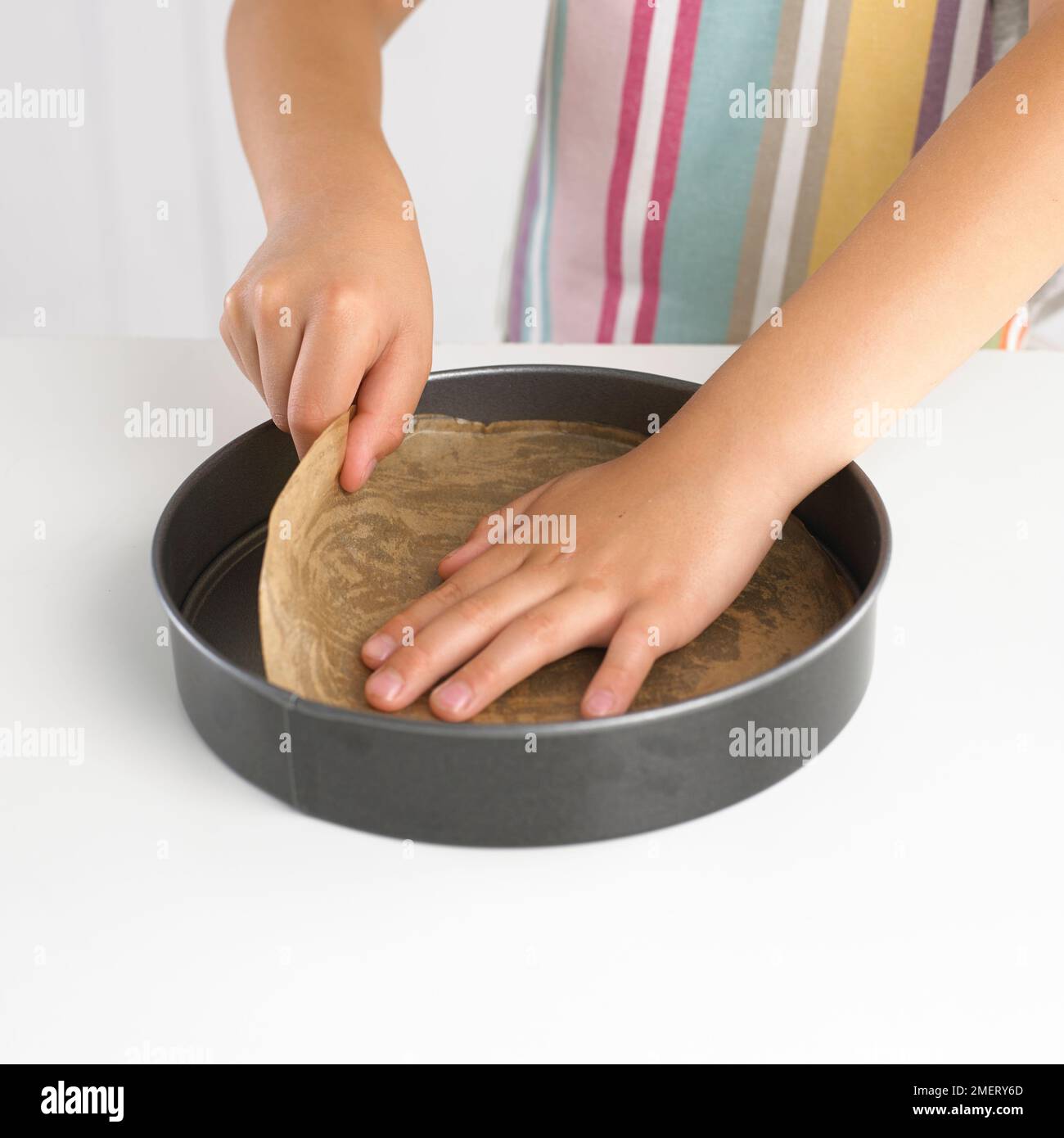 Boy placing greaseproof paper in bottom of cake tin Stock Photo Alamy