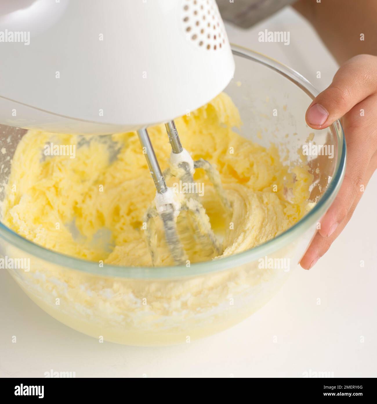 Boy mixing butter and sugar together with electric whisk Stock Photo