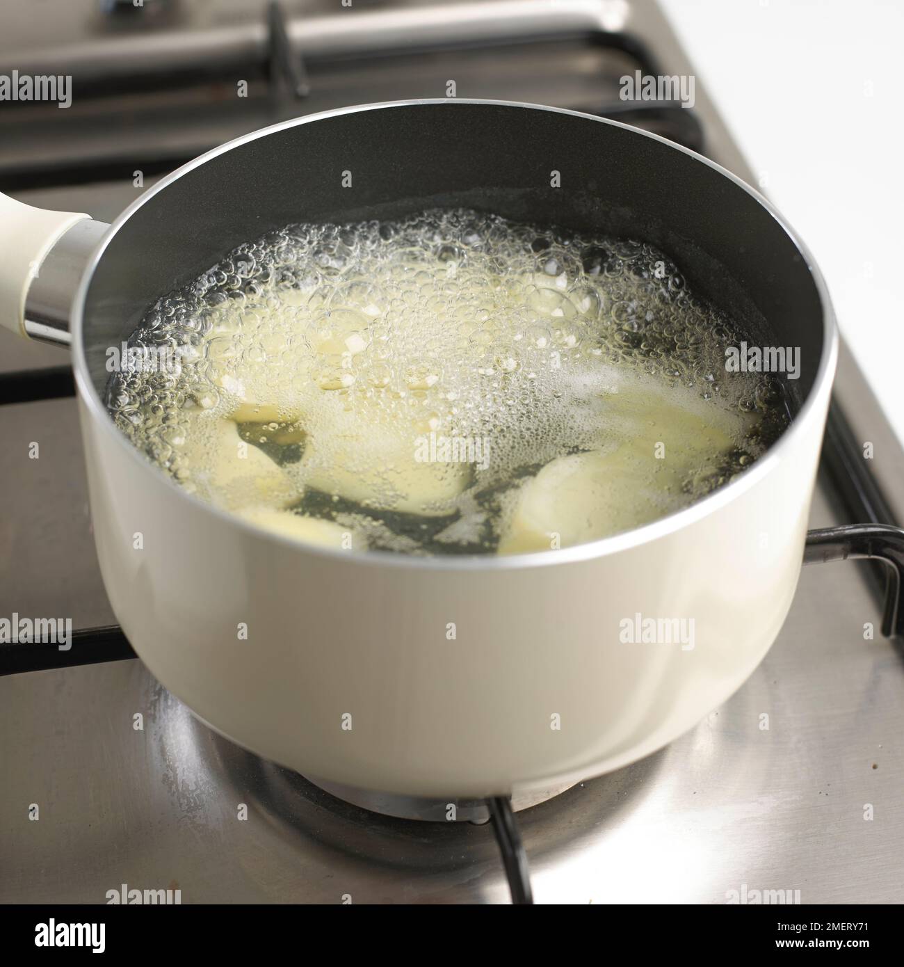 Potatoes cooking in boiling water in a saucepan on cooker Stock Photo