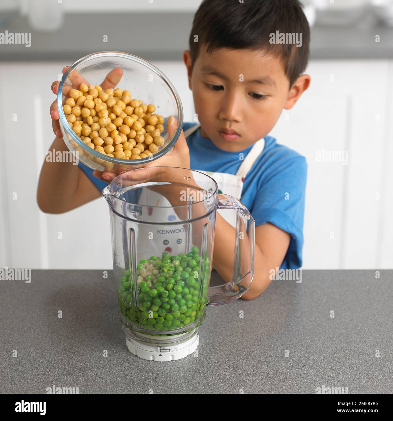 Making pea hummus, Boy pouring chickpeas into jug of peas, 4 years ...