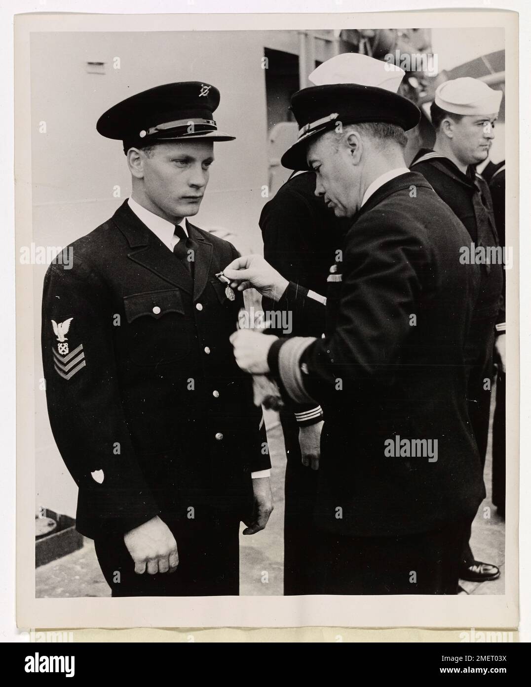 William H. Mueller, a Boatswain's Mate from Milwaukee, Wisconsin, is awarded the Navy and Marine Corps Medal for his heroic efforts in the salvage of a flaming tanker carrying high octane aviation gasoline. His actions played a crucial role in saving the vessel. Stock Photo