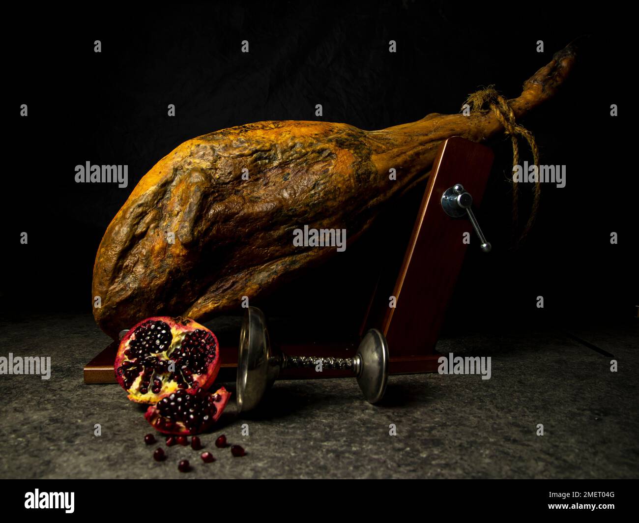 whole leg of jamon with pomegranate on black background Stock Photo