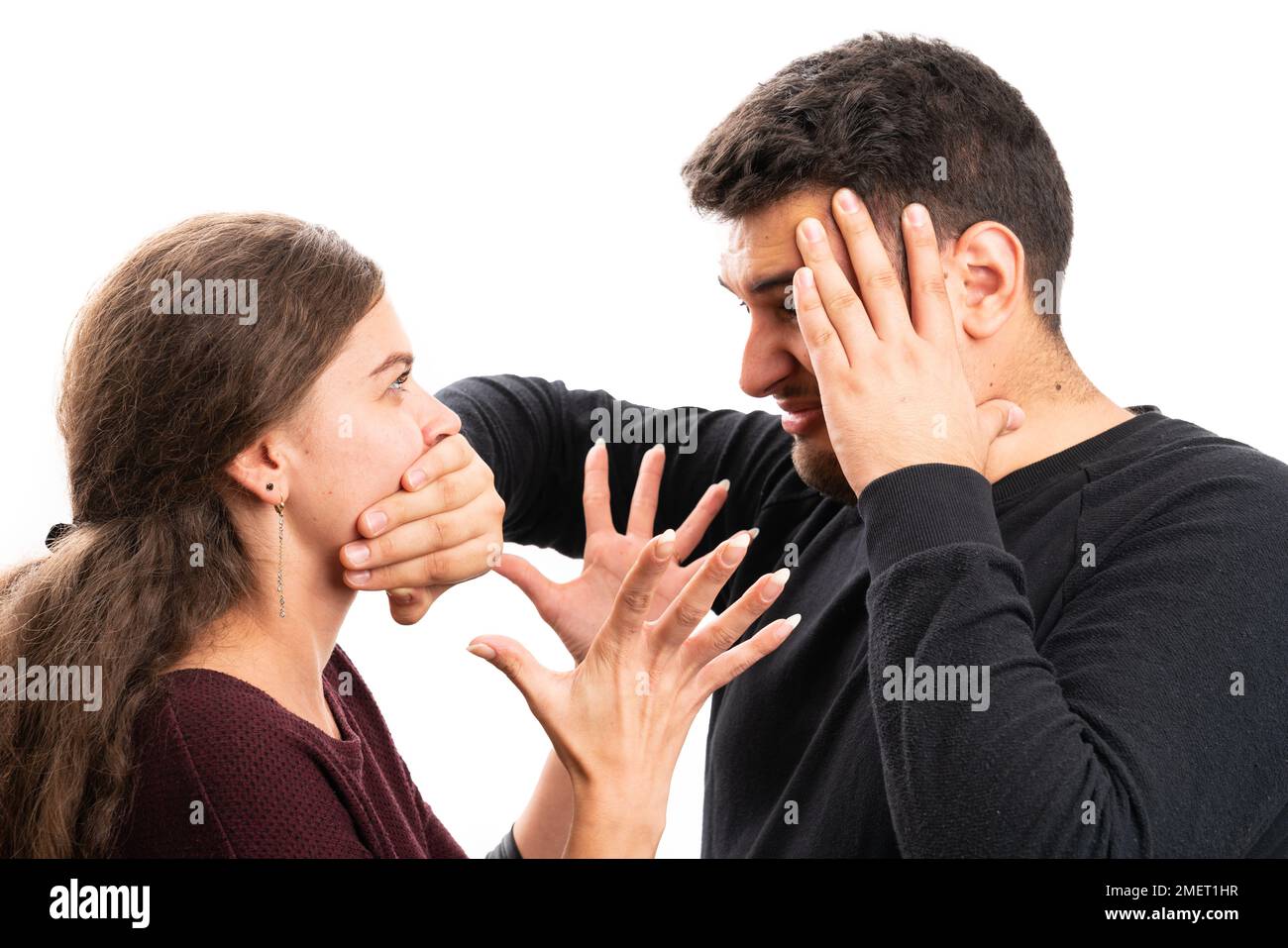 Angry boyfriend covering yelling girlfriend mouth using hand as arguing couple relationship concept isolated on white studio background Stock Photo
