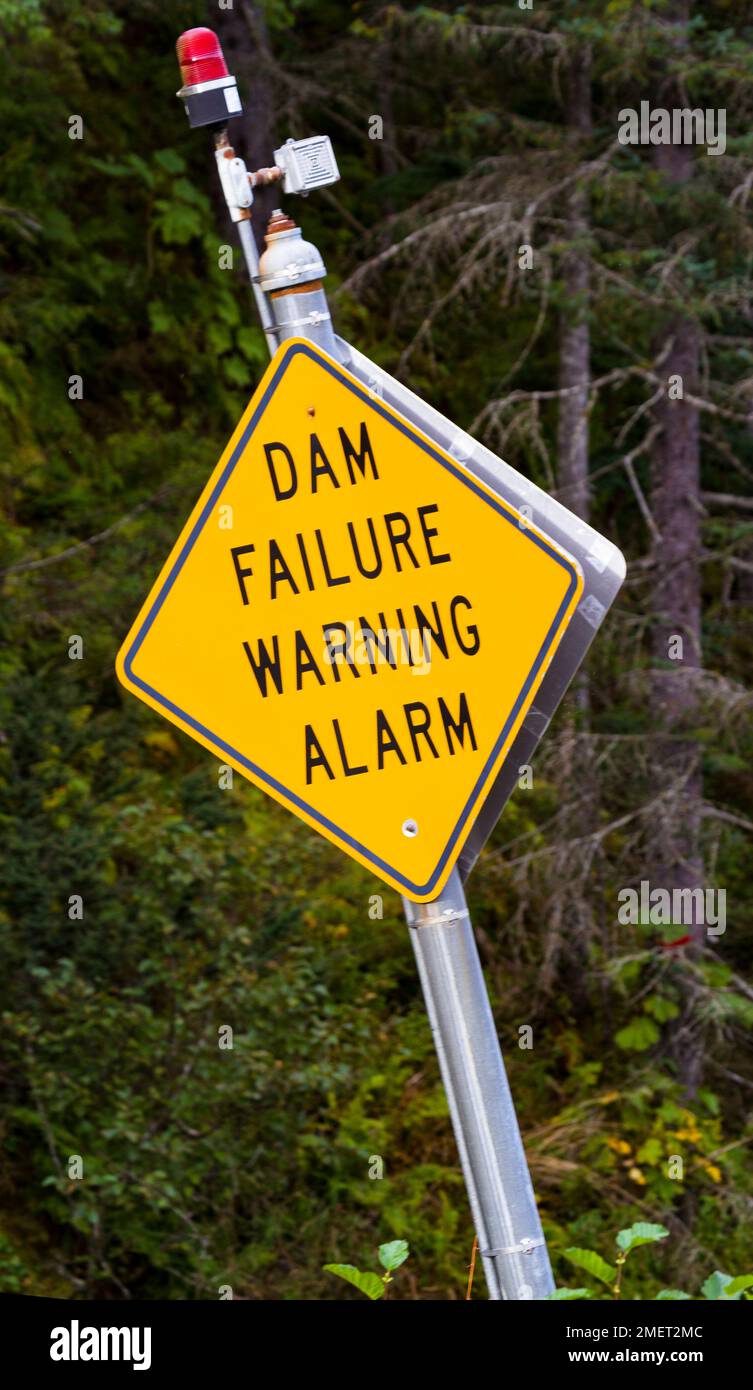 Badly tilted DAM FAILURE WARNING ALARM sign with red danger light in remote Valdez, Alaska, United States Stock Photo