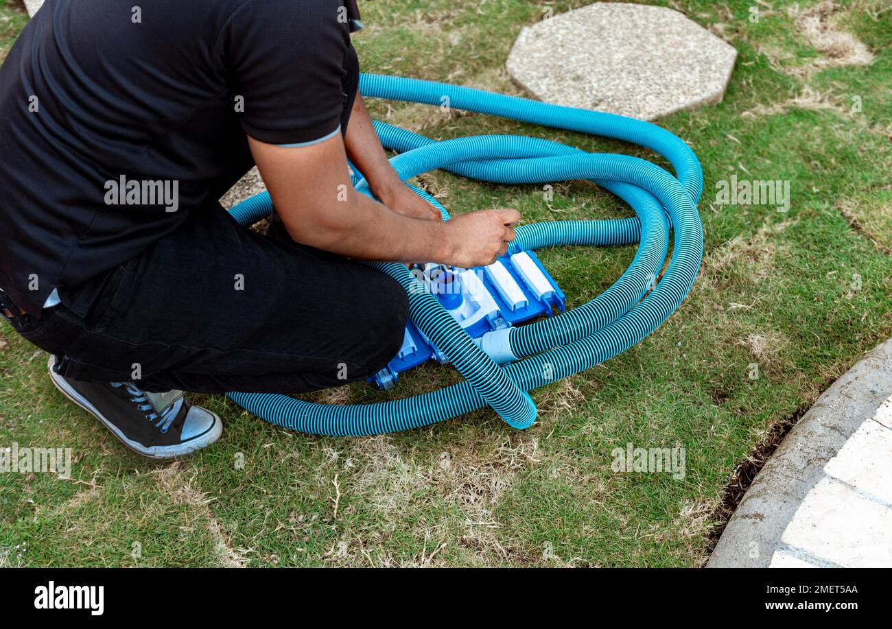 Man connecting the handle on the pool vacuum. Suction equipment