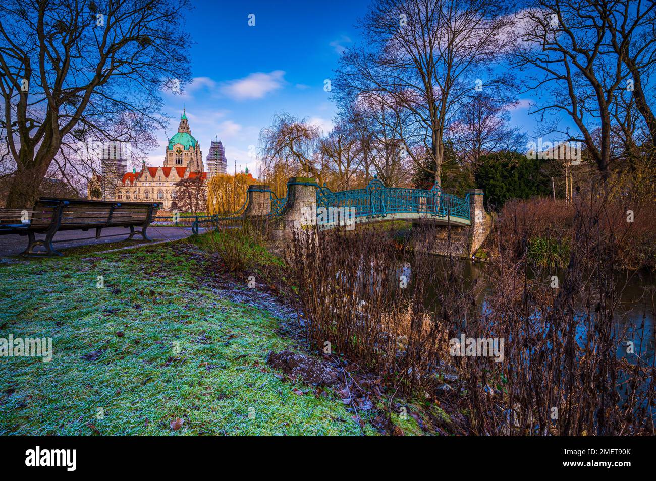 The heritage-protected Maschpark bridge, a park bench and the new city hall in the background with blue sky and scattered clouds, Hanover, Lower Stock Photo