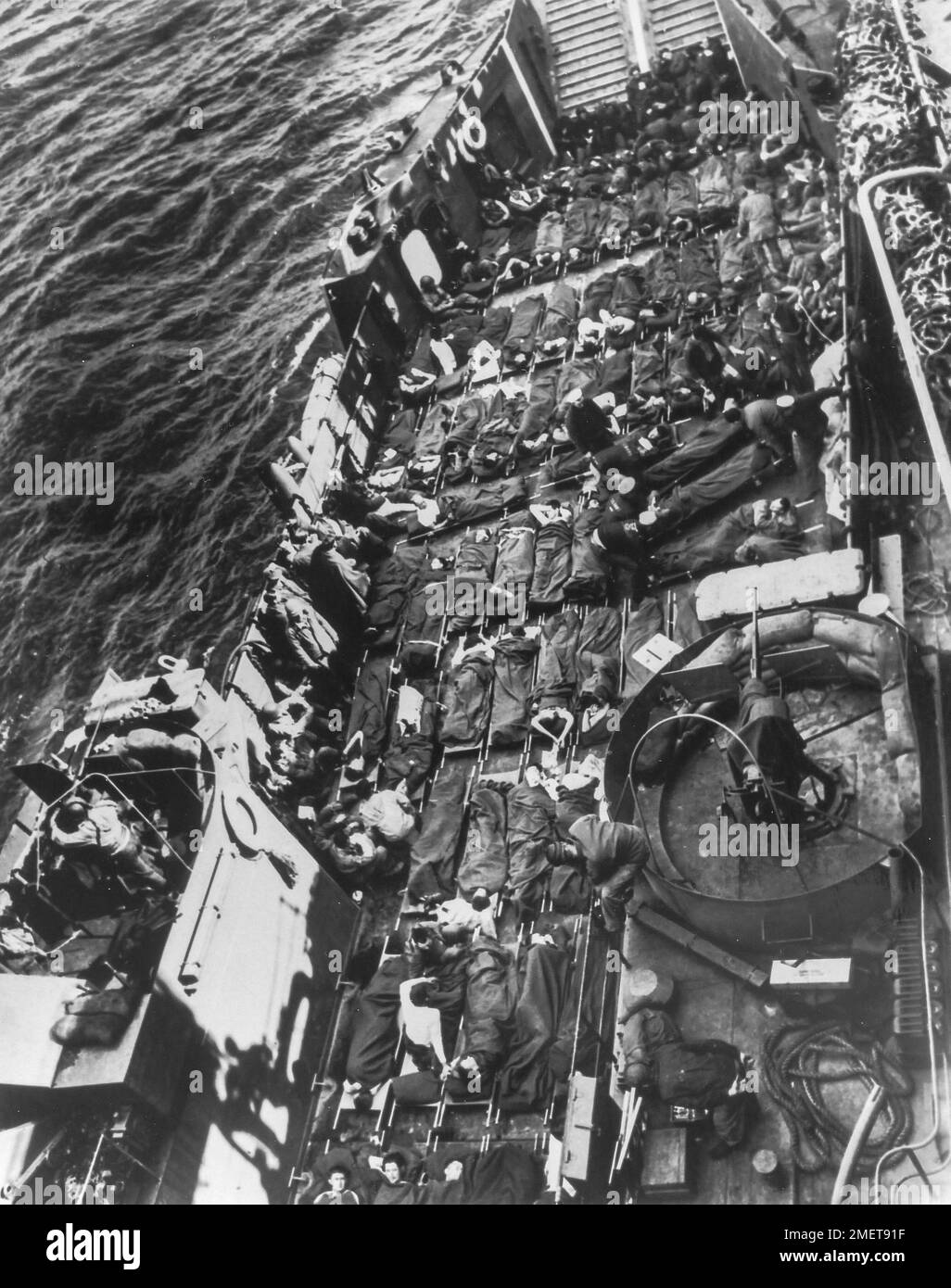 Photograph of Stretchers Covering the Decks of a Coast Guard LCT. Beachheads Come High- Row upon row of stretchers cover the decks of a Coast Guard LCT bringing out wounded invaders from the flaming soil of France. These American and British soldiers fell somewhere between the beachhead and Cherbourg as Nazi defenders sought a high price in casualties for every yard they yielded. The wounded are being transferred to a Coast Guard assault transport which will carry them back to England for hospitalization. 1939 - 1967. Stock Photo