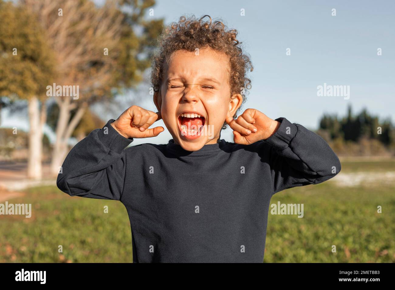 little boy outdoors covering his ears Stock Photo Alamy