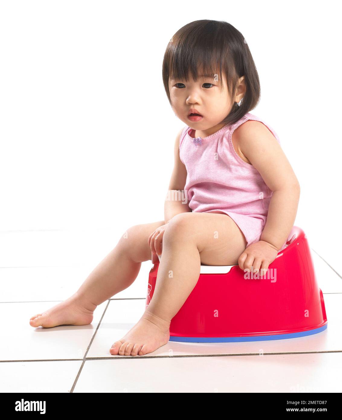 Girl wearing pink vest sitting on a red potty, 20 months Stock Photo ...