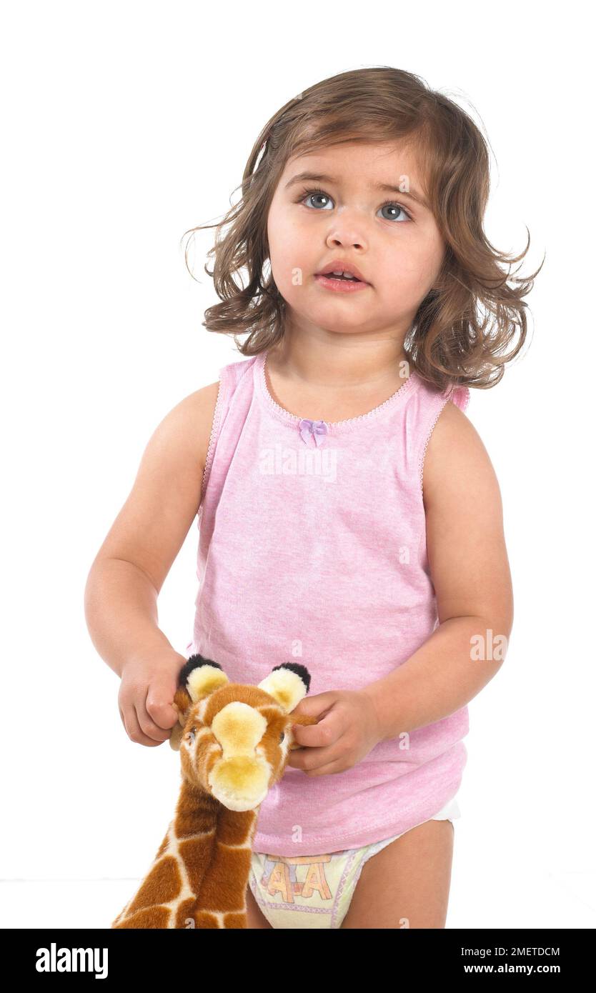 Girl wearing pink vest and nappy holding giraffe toy, 20 months Stock Photo