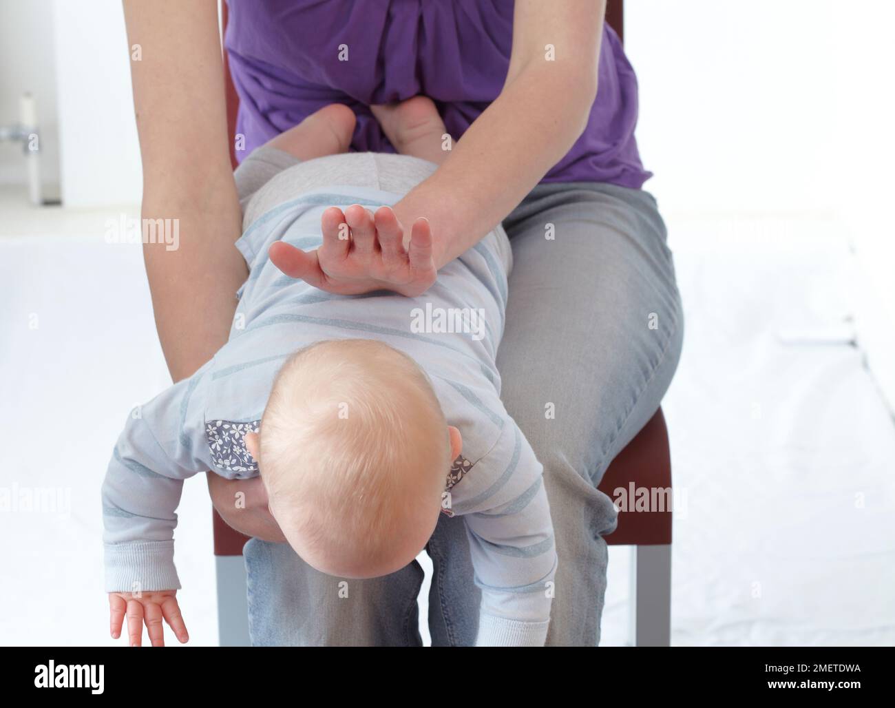 First aid treatment of choking infant, slapping on back Stock Photo