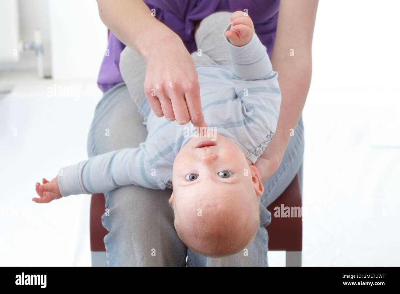 First aid treatment of choking infant, checking mouth and picking out