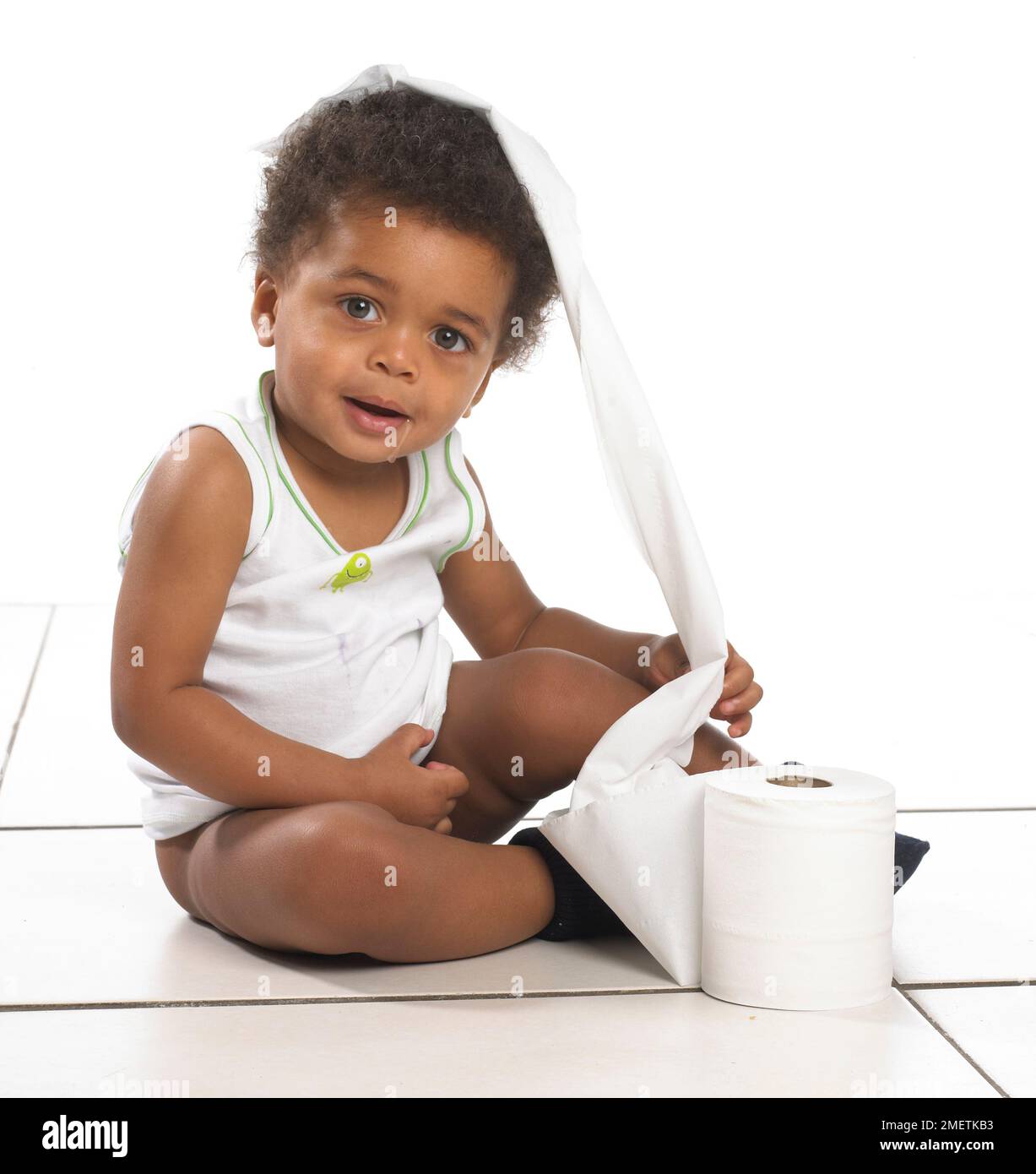Boy wearing vest sitting on floor with toilet paper on head, 17 months Stock Photo