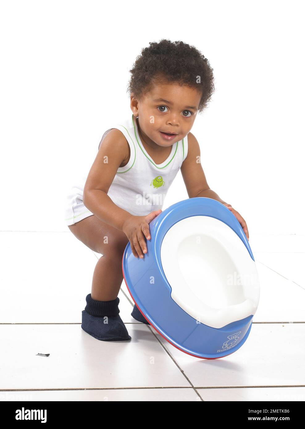 Boy in vest and slippers holding a blue potty, 17 months Stock Photo