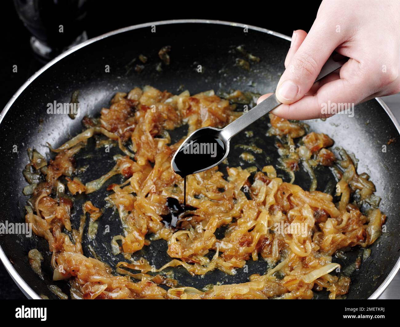 Cooking onion marmalade, adding balsamic vinegar Stock Photo