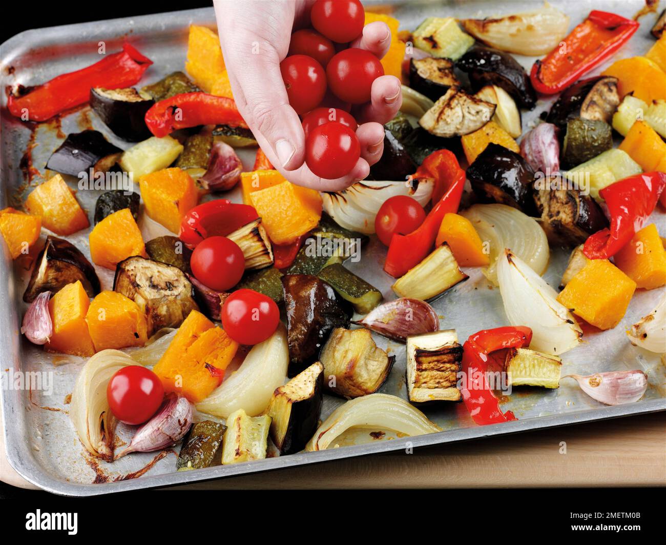 Adding cherry tomatoes to roasted vegetables (courgettes, aubergines
