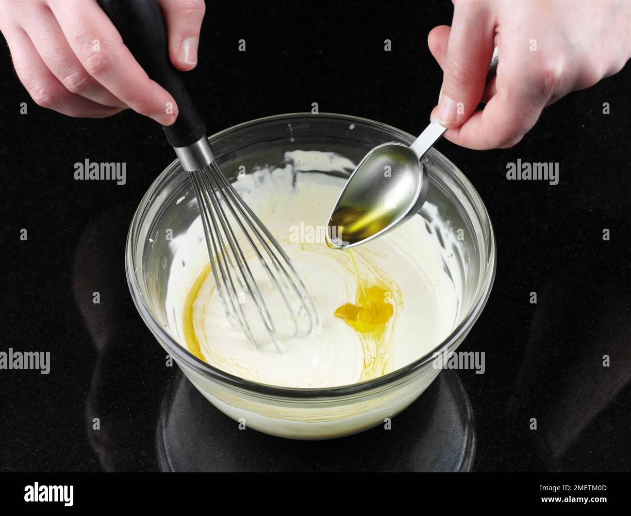 Making dressing for Caesar salad, stirring olive oil into mayonnaise