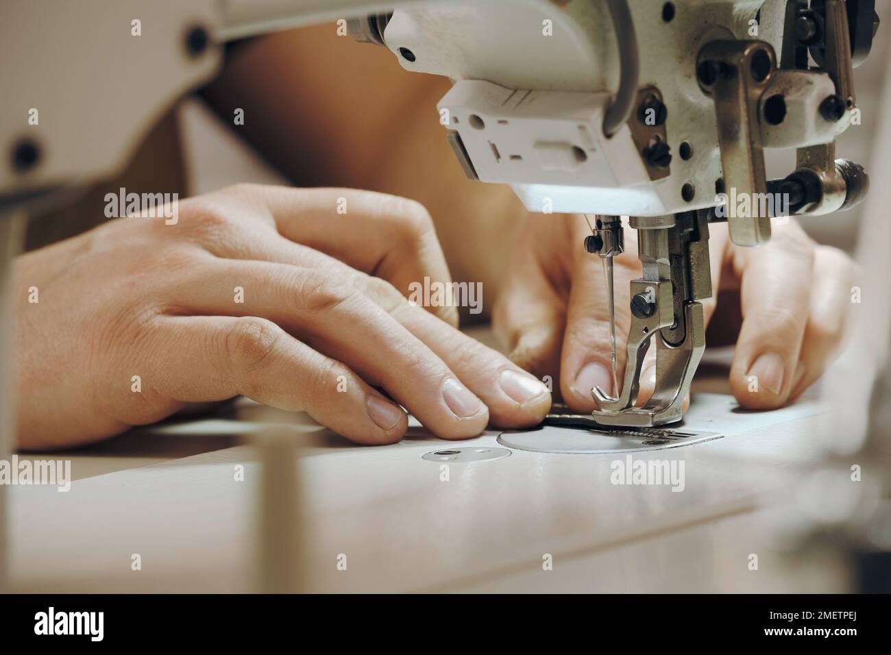 Tailor sewing at workplace. Man hands sewing on machine at his studio