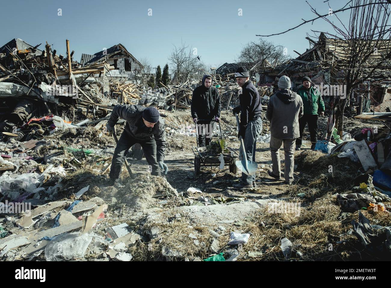 Serhiy Melnyk, right, in green jacket, cleaning up with his neighbours in the ruins of the Bohunia neighbourhood, which was destroyed by a Russian Stock Photo