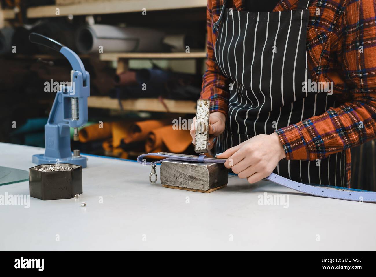 Sewing process. Cropped view of the tailor making holes for the buckle