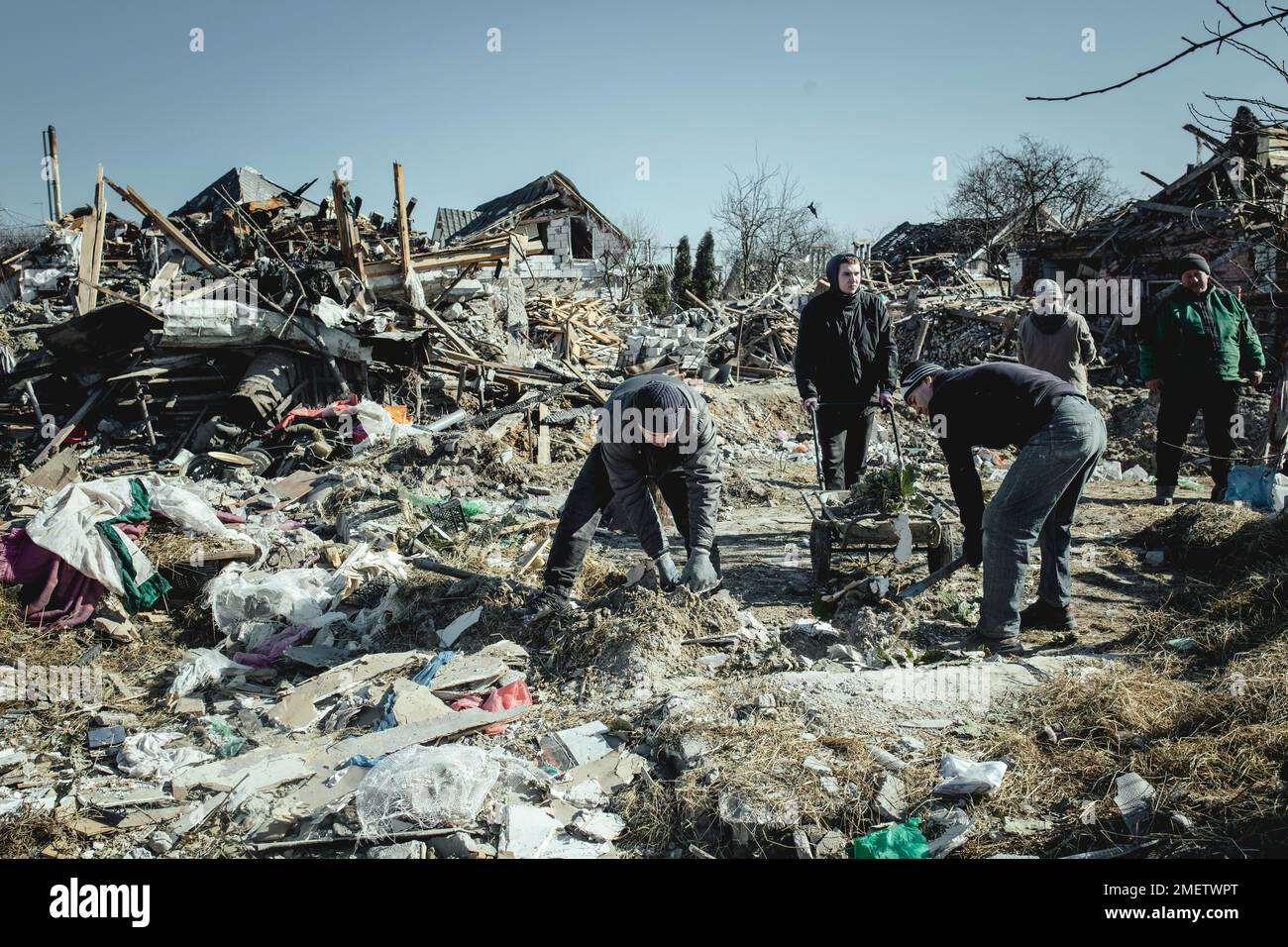 Serhiy Melnyk, right, in green jacket, cleaning up with his neighbours in the ruins of the Bohunia neighbourhood, which was destroyed by a Russian Stock Photo
