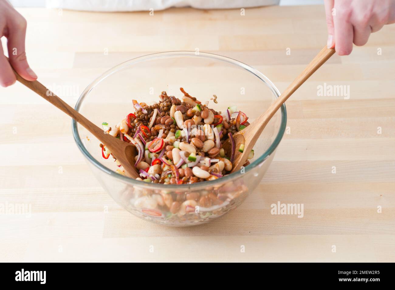 Making lentil and chilli bean salad, tossing ingredients together Stock Photo