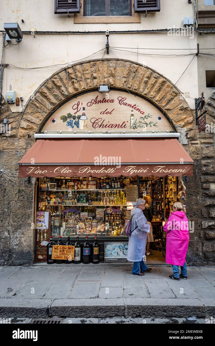 Two woman in rain jackets talking outside of souvenir shop in Florence, Tuscany, Italy. Stock Photo