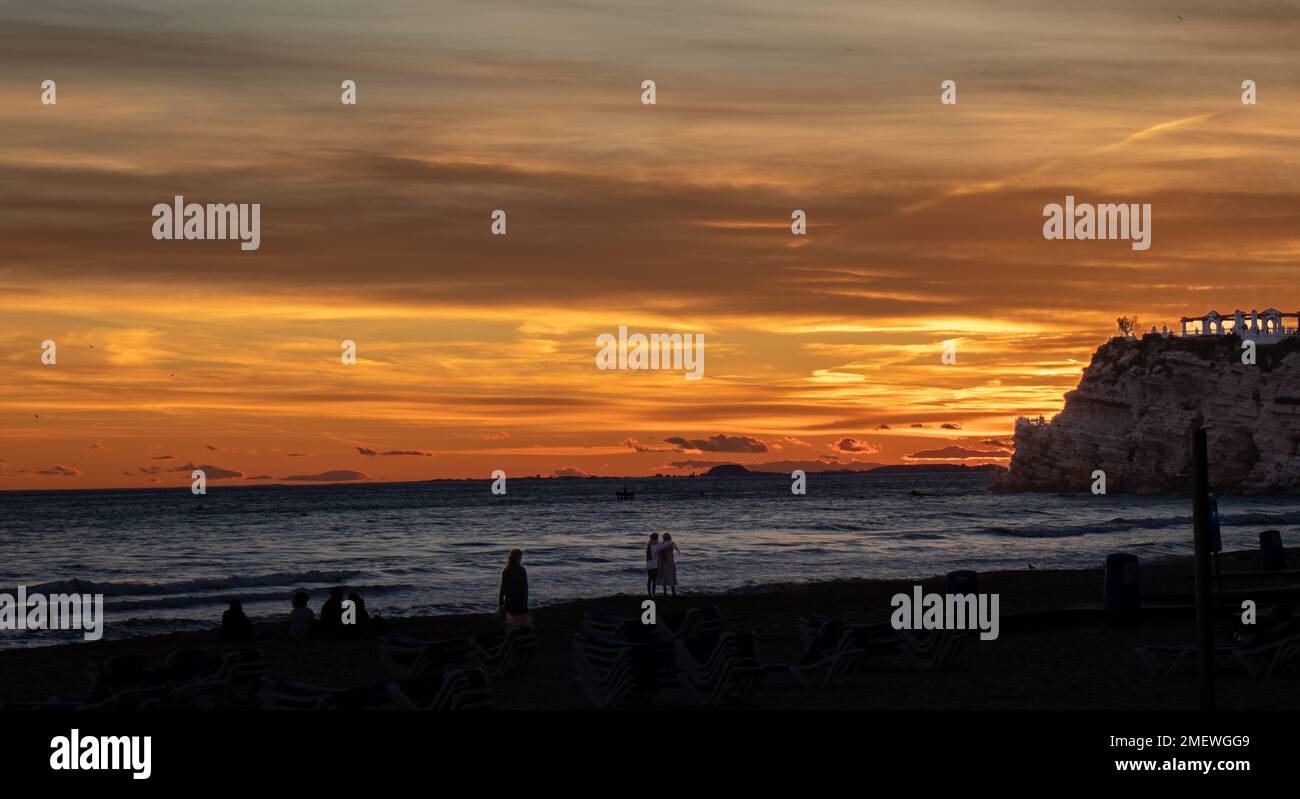 Atardecer en Benidorm en la playa de Poniente con las siluetas de las personas que lo disfrutan. Stock Photo