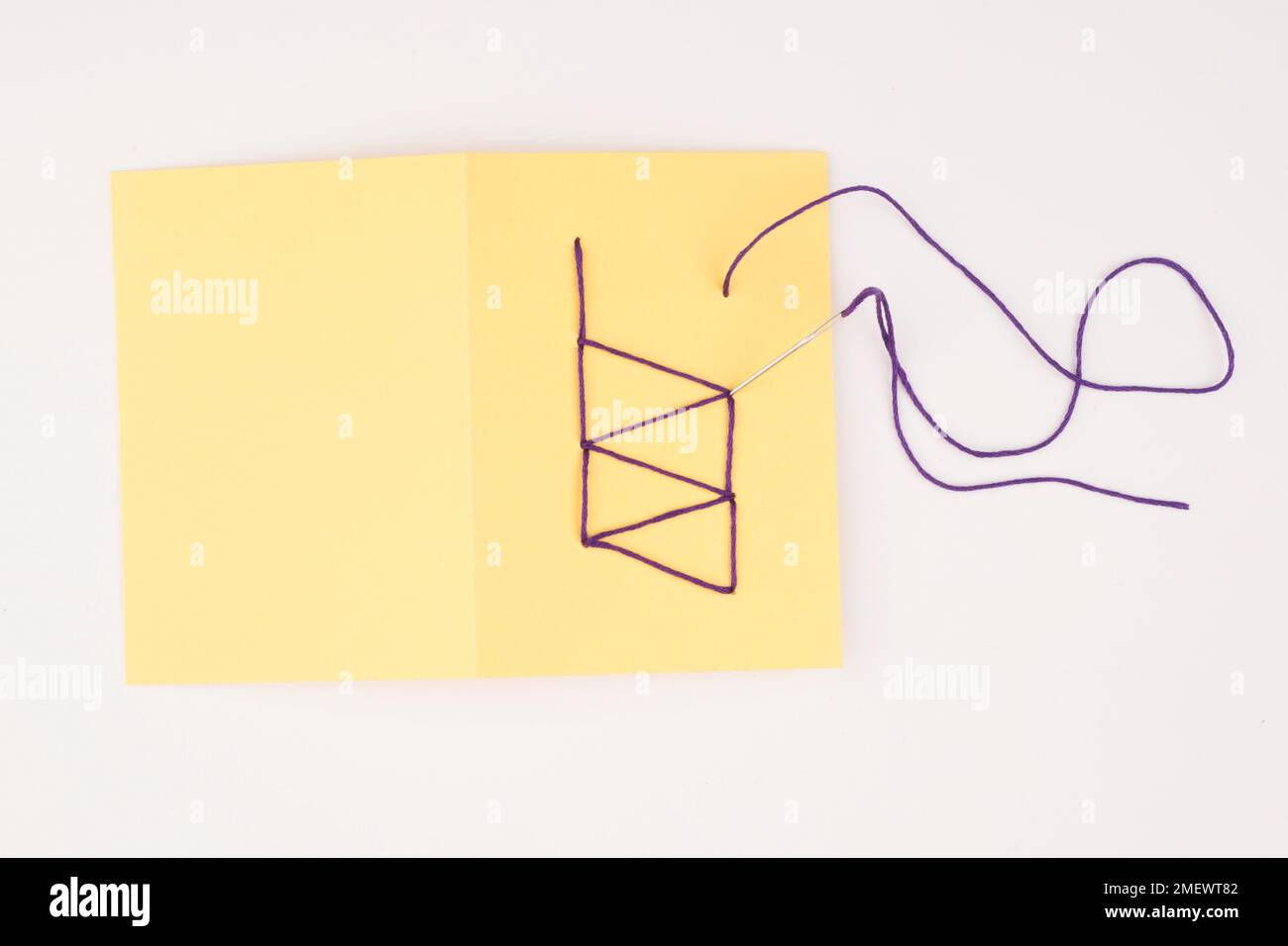 Sewing a design onto card with a needle and thread Stock Photo - Alamy