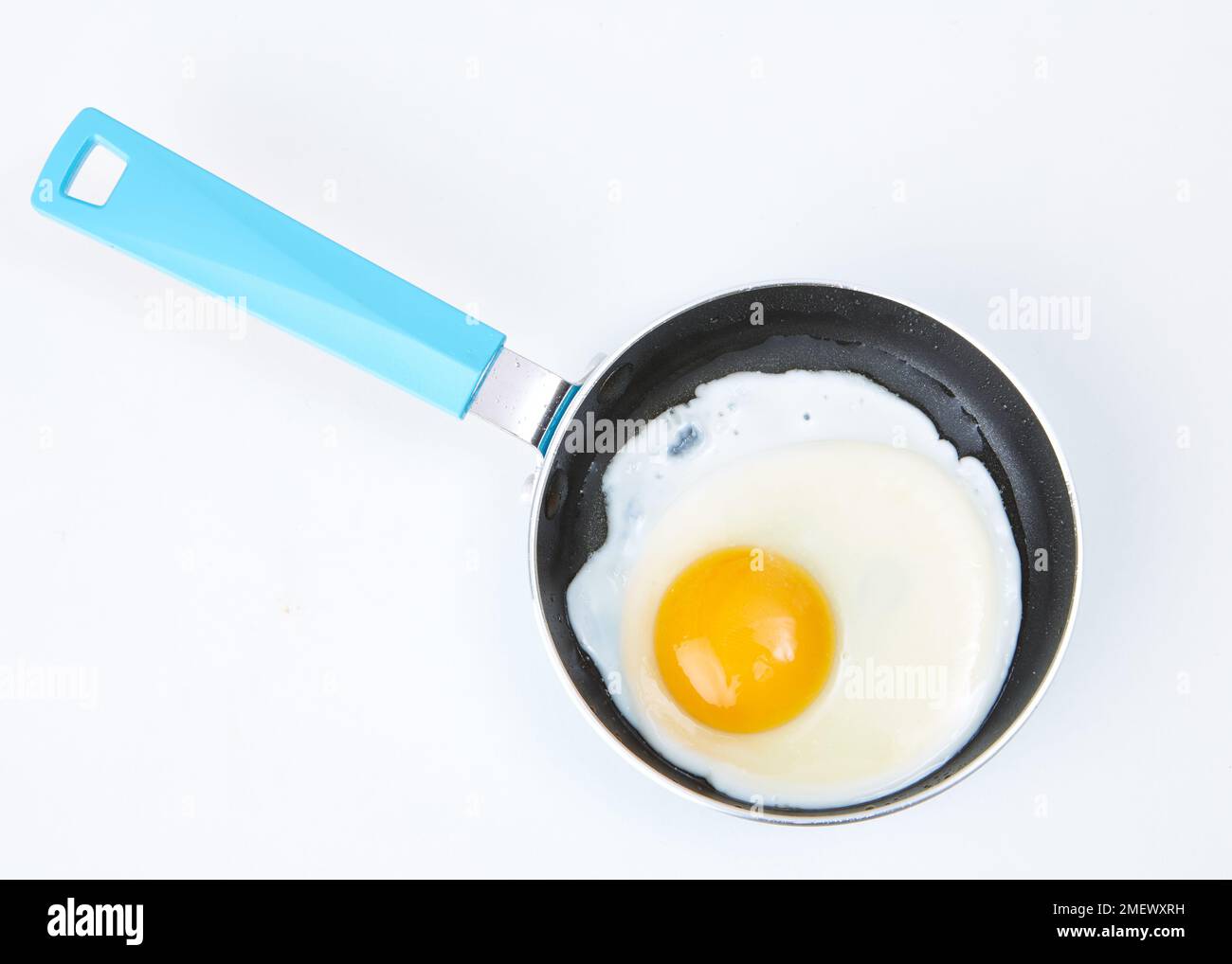 Egg being cooked in blue frying pan Stock Photo Alamy