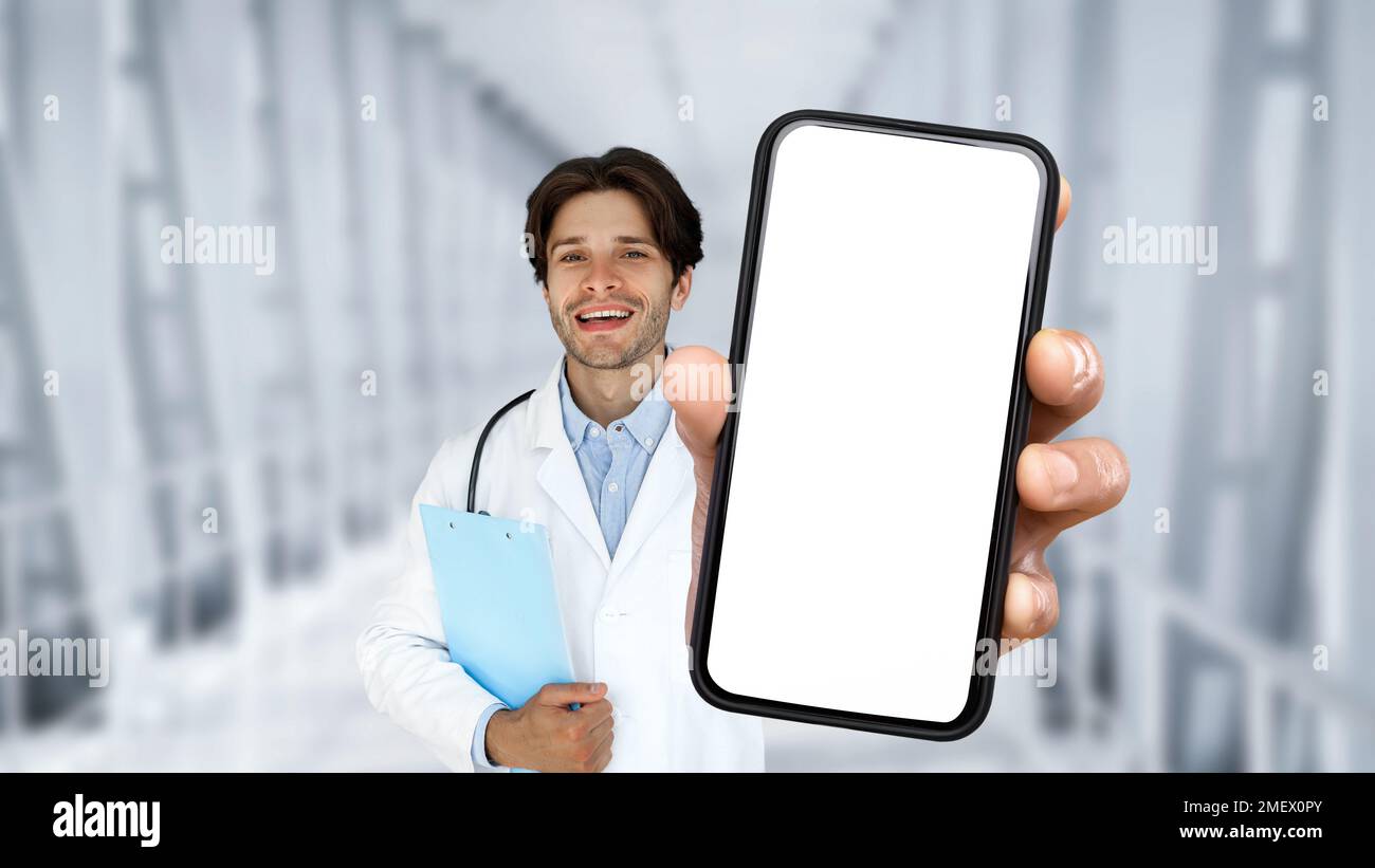 Medical Insurance. Handsome Male Doctor Holding Smartphone With Blank Screen In Hand Stock Photo