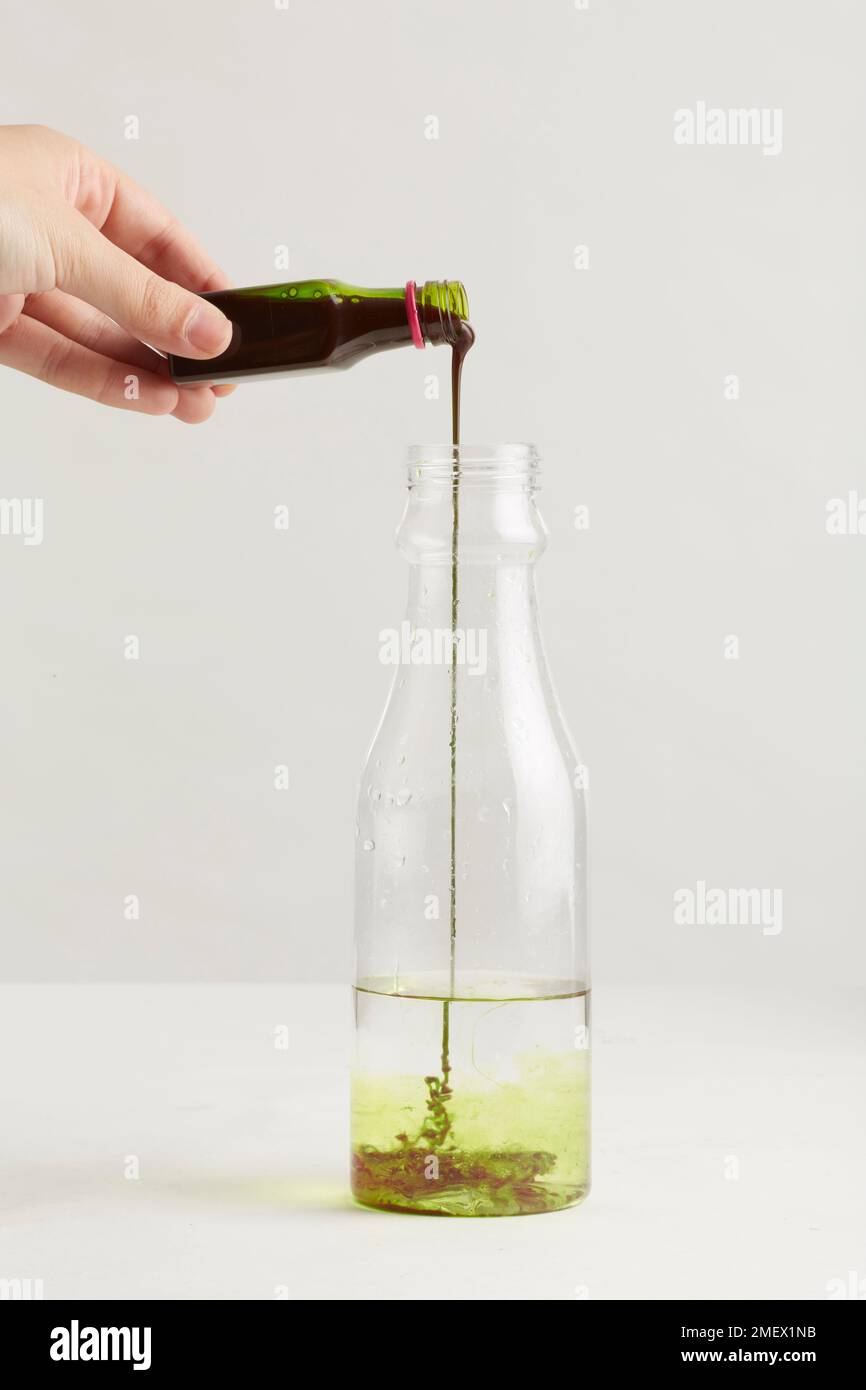 Adding food colouring to water in a glass jar Stock Photo
