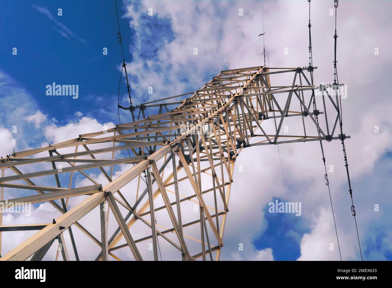 High voltage power pylons against blue sky and sun rays Stock Photo - Alamy
