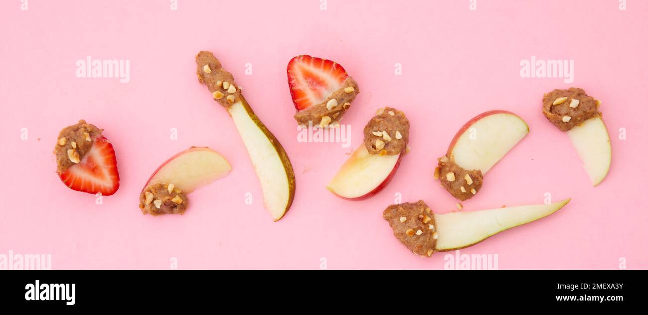 Bowl of almond butter dip on pink background with stripy tea towl and fruit to dip Stock Photo
