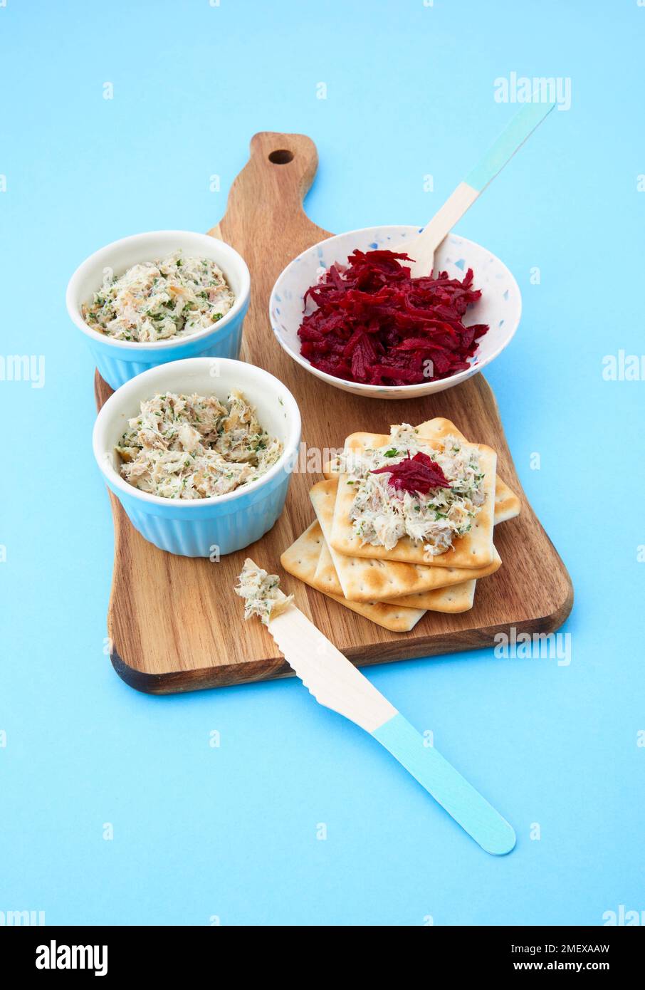 Smoked mackrel pate in ramekins on chopping board with beetroot and crackers Stock Photo