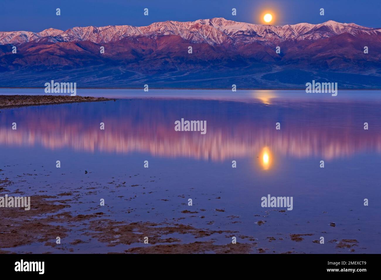 Reflections in Badwater Basin lake, Moonrise over Panamint Mountains and Badwater Basin, Death Valley National Park, California, USA Stock Photo