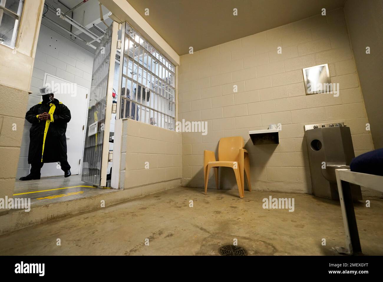 A corrections officer passes by a holding cell holding cell near the