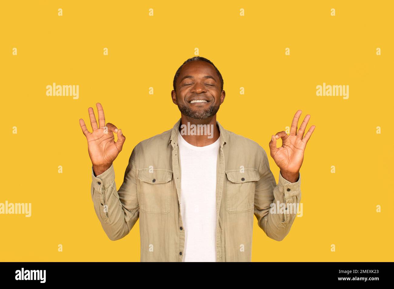 Happy peaceful mature african american man in casual with closed eyes meditation, enjoy calm, rest Stock Photo