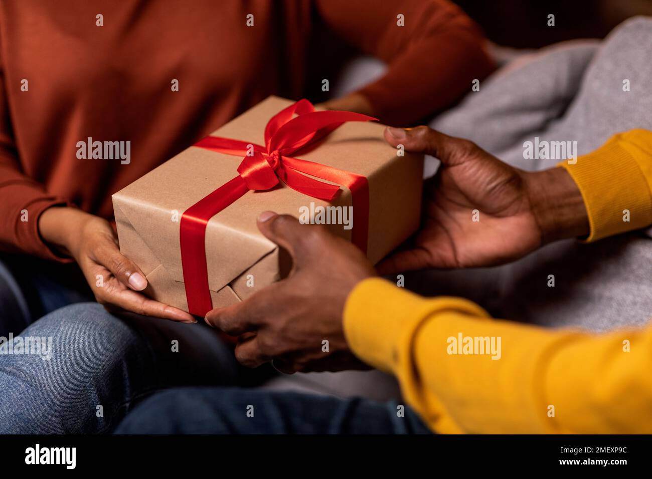 Cropped of black man and woman exchanging presents at home Stock Photo