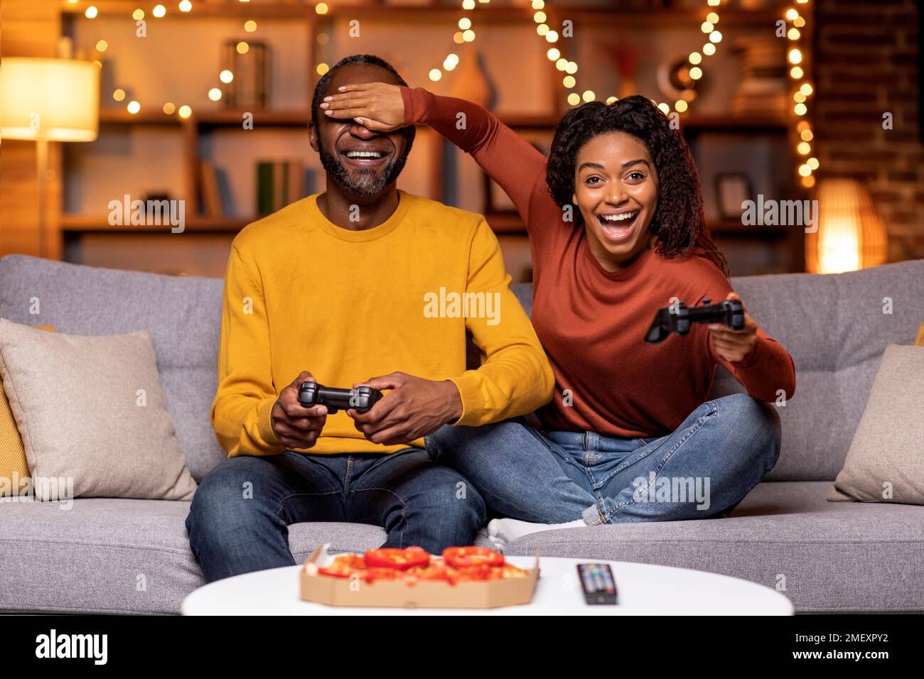 Positive funny black couple playing video games at home Stock Photo