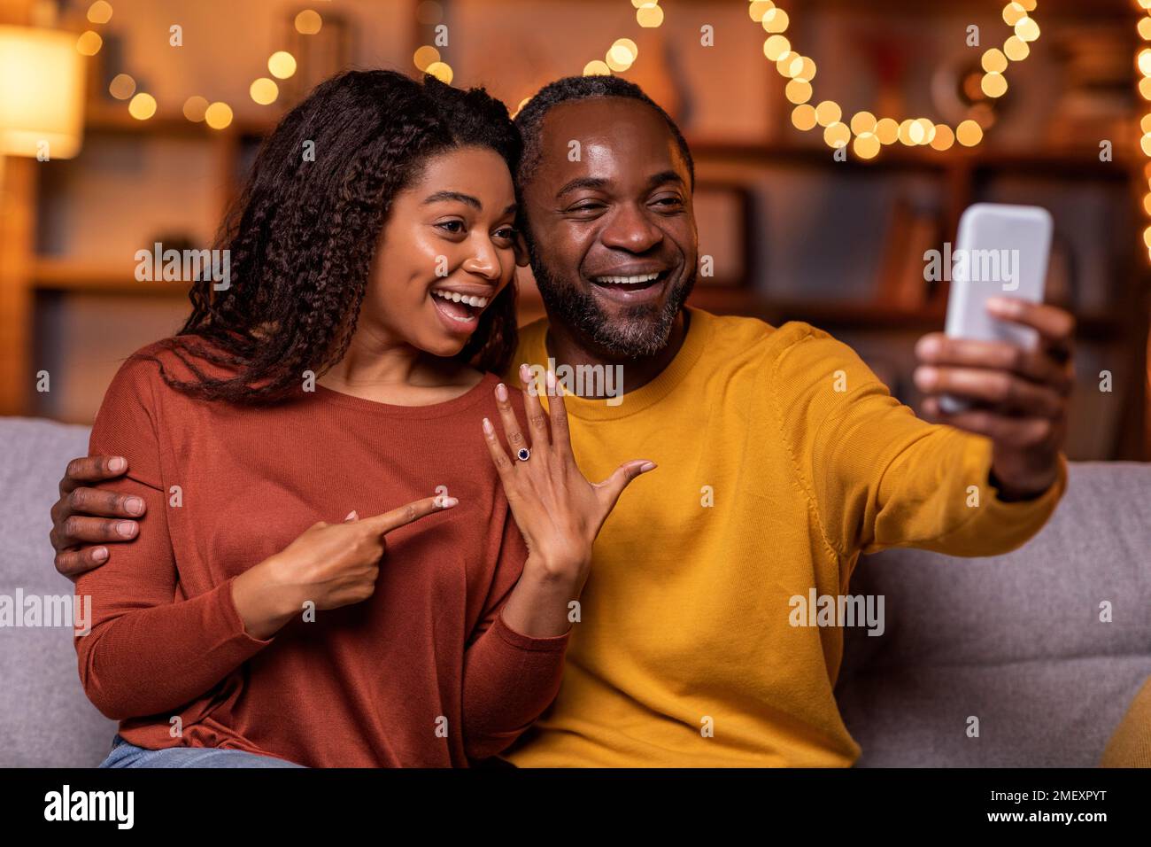 Happy black couple got engaged, taking selfie on smartphone together Stock Photo