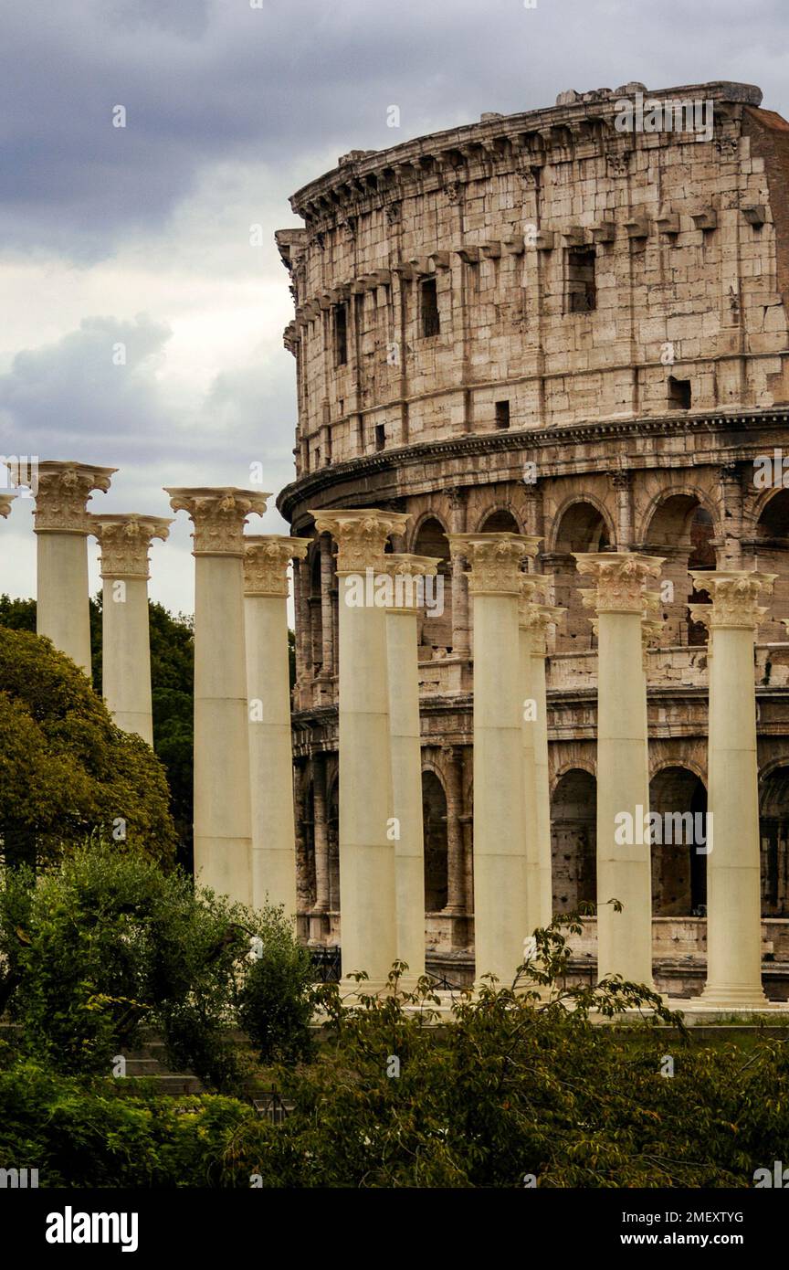 Rows of Roman pillars or columns in the foreground, and the Colosseum amphitheater in the background. Stock Photo