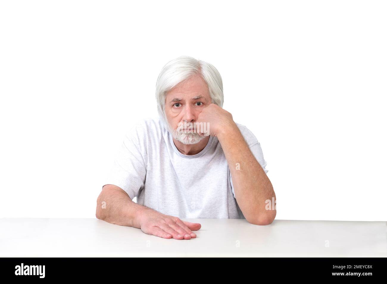 Horizontal shot of a bored white haired man sitting with his fist on his cheek.  White background.  Lots of copy space. Stock Photo