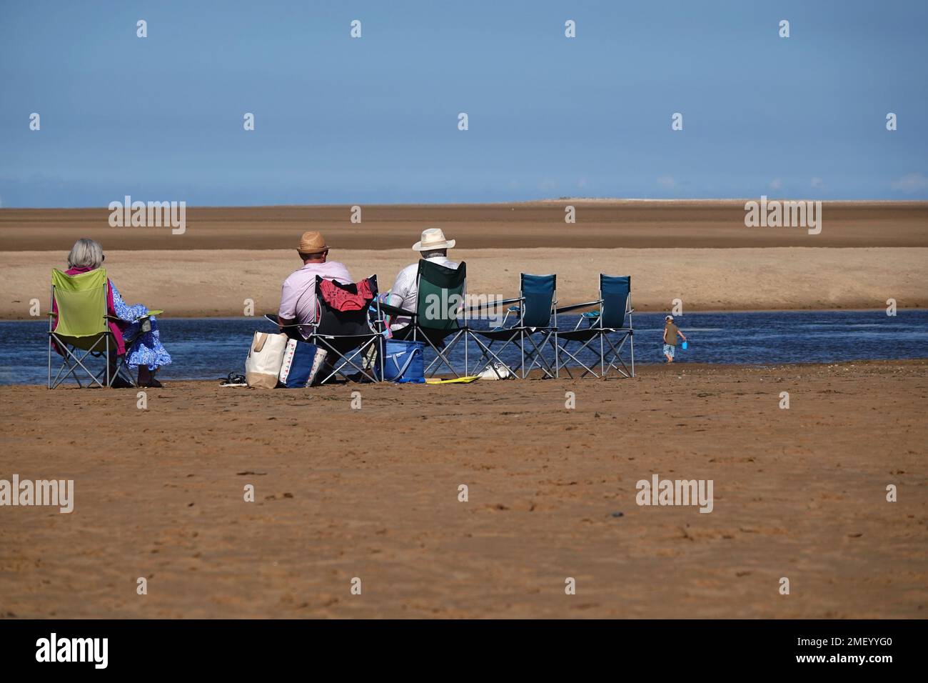 A group of seniors sitting on a vast empty beach in the summer Stock ...