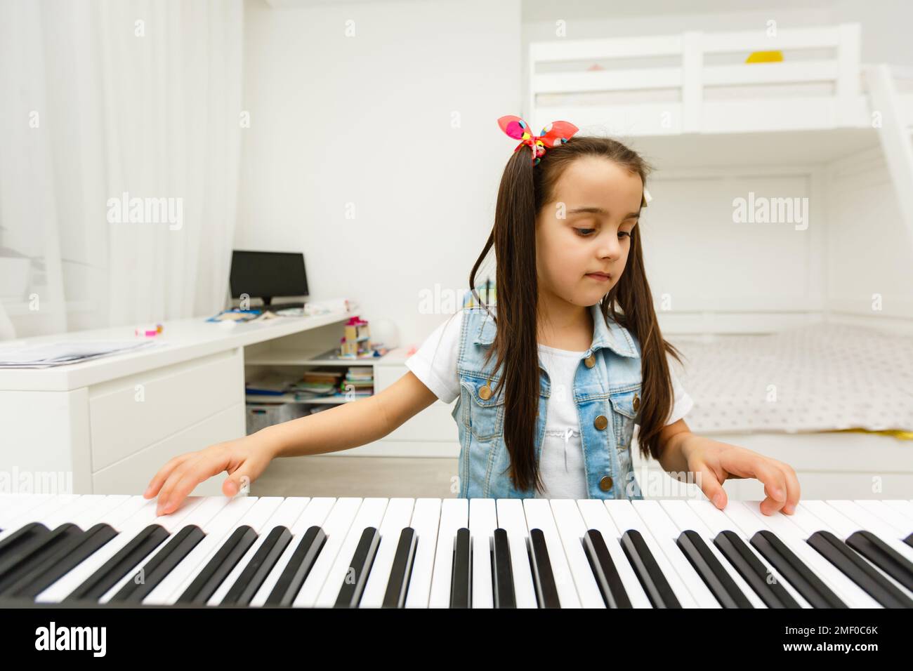 Home lesson on music for the girl on the piano. The idea of activities for the child at home during quarantine. Music concept Stock Photo