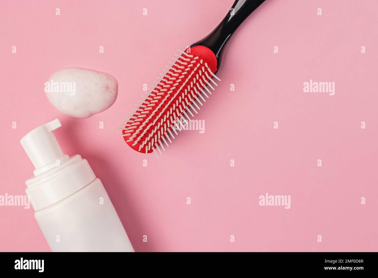 Brush and foam for curly hair styling. Hairstyle products on pink
