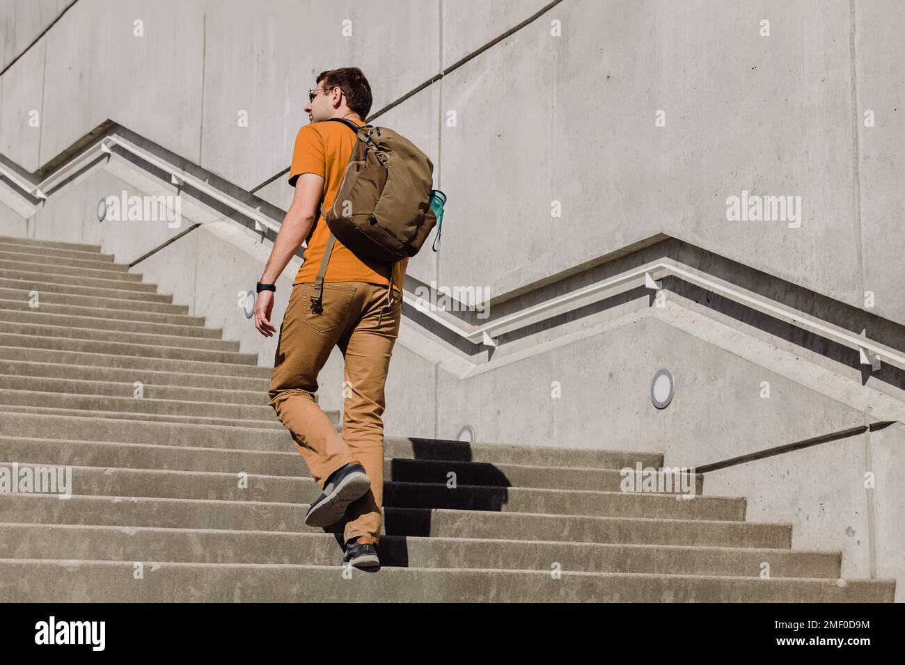Young man with a backpack walking, going up the stairs in the city ...
